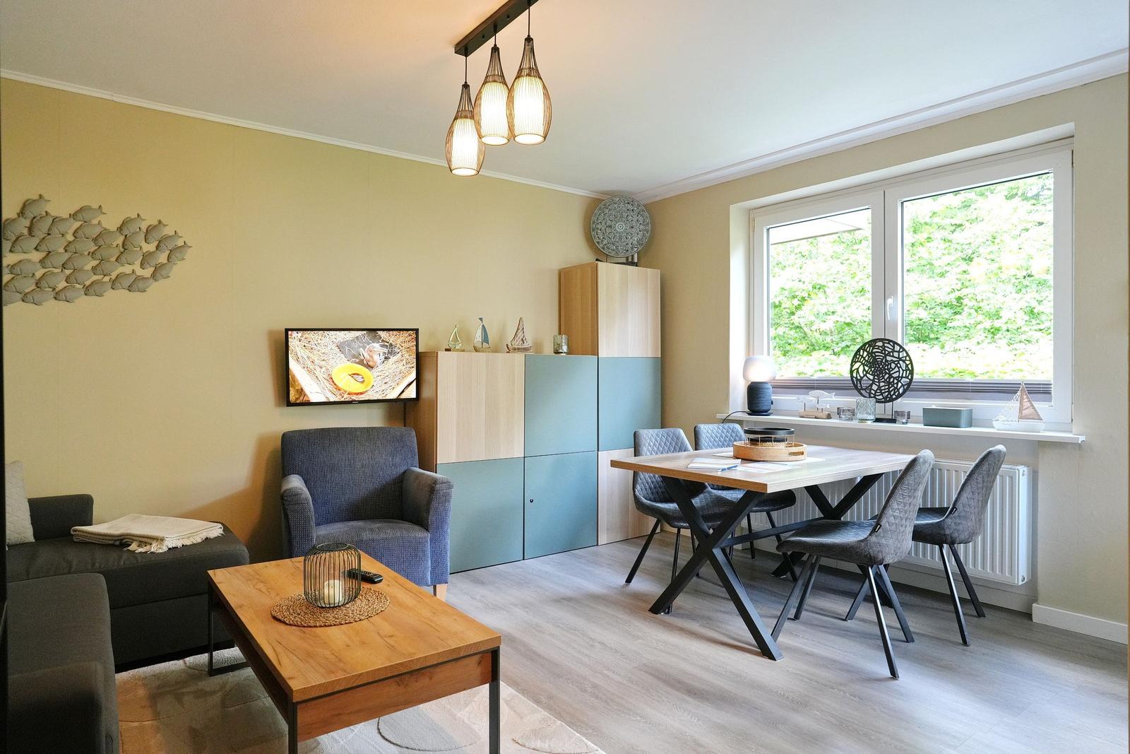 Wohn- und Essbereich mit Holztisch, Stühlen und Fernseher an der Wand.