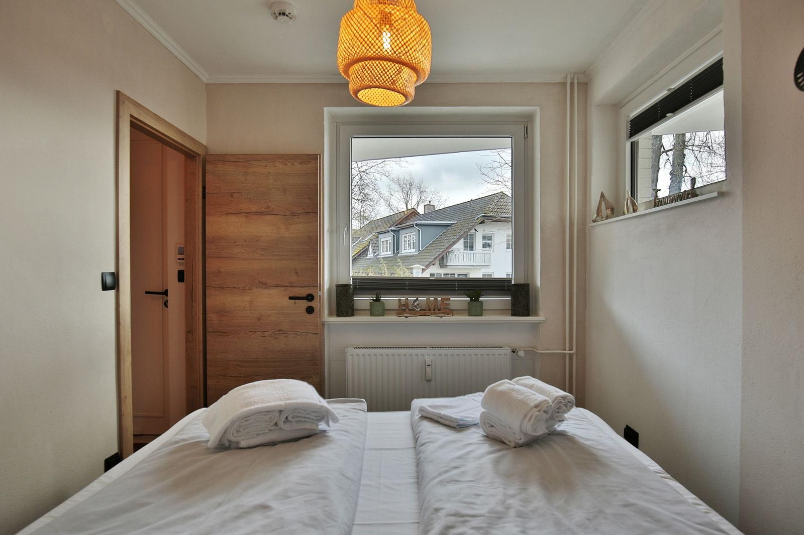 Zimmer mit zwei Betten, Fensterblick auf Haus und Hängelampe