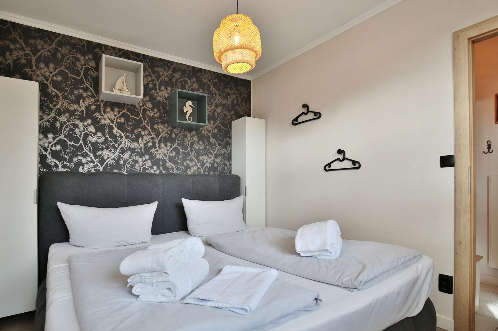 Schlafzimmer mit Doppelbett, dekorativer Wandtapete und Lampe.