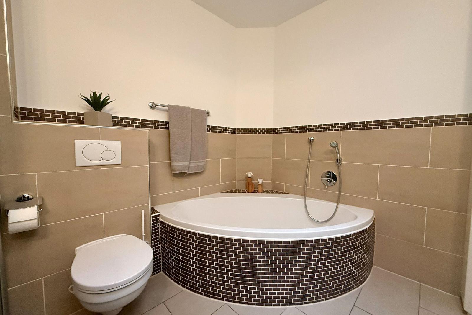 Badezimmer mit Badewanne, Toilette und Handtuchhalter.