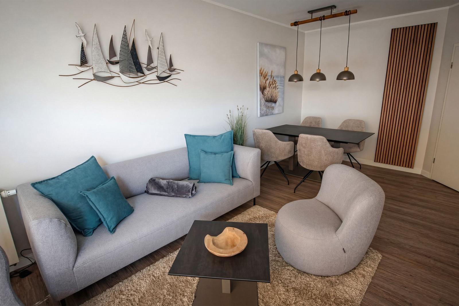 Wohn- und Essbereich mit Sofa, Sessel, Tisch und Wanddekoration.
