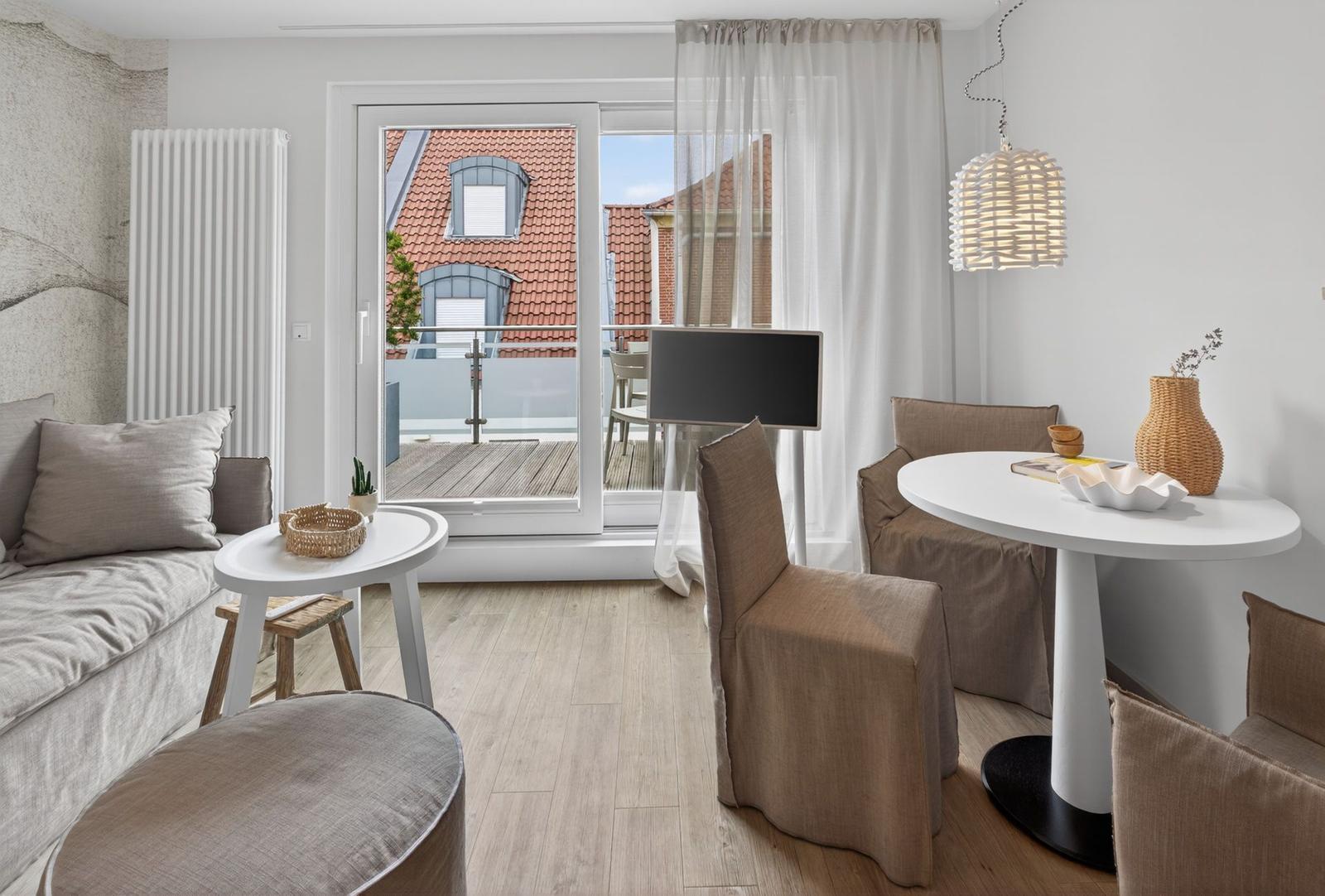 Wohnbereich mit Sitzgruppe, Esstisch und Balkonansicht auf Dachterrassen.