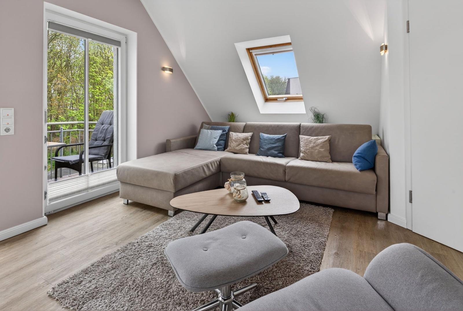 Wohnzimmer mit Ecksofa, Terrasse und Dachfenster. Holzboden und Teppichboden.