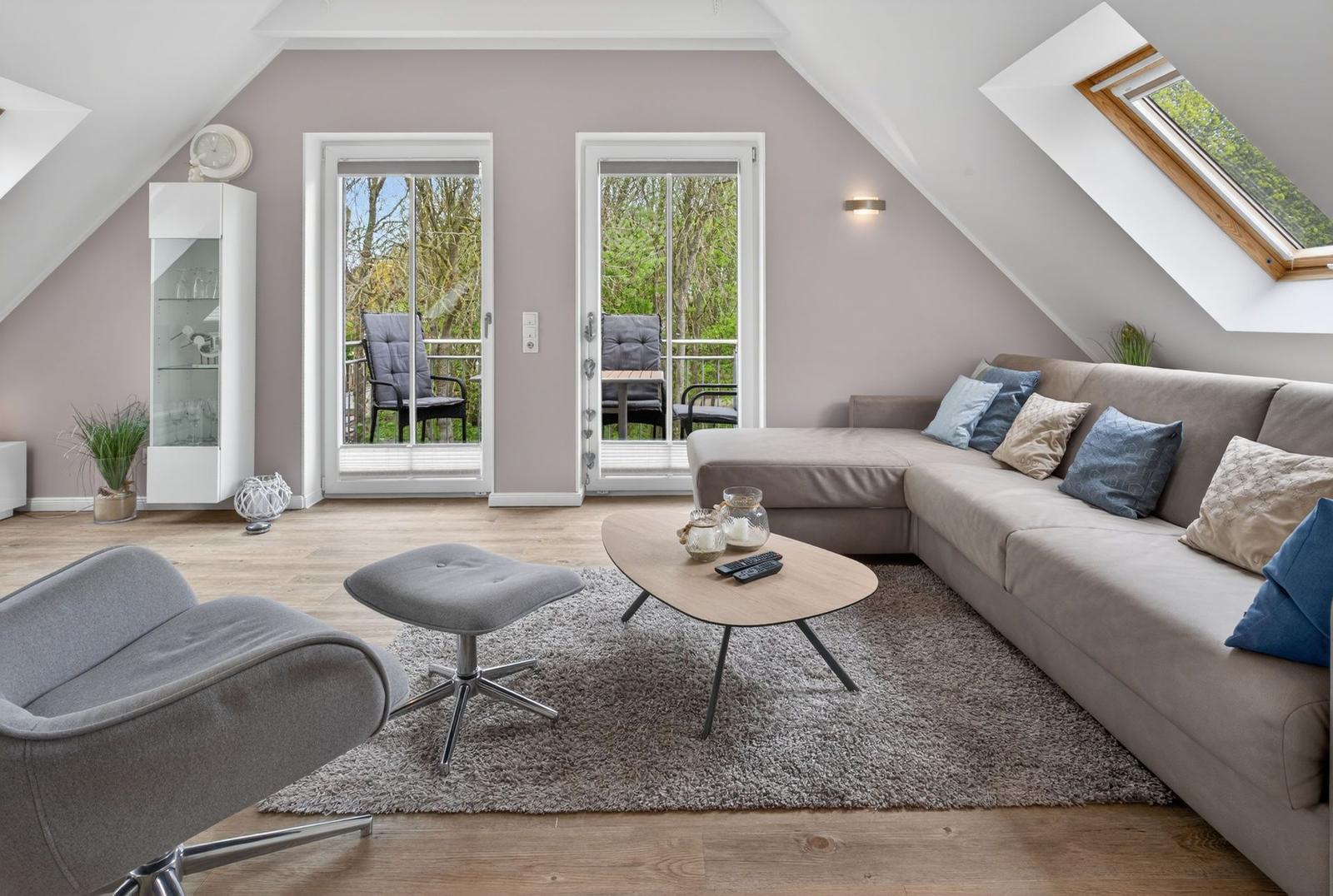 Wohnzimmer mit Ecksofa, Glasfront und Dachfenster. Holzboden und graue Polster.