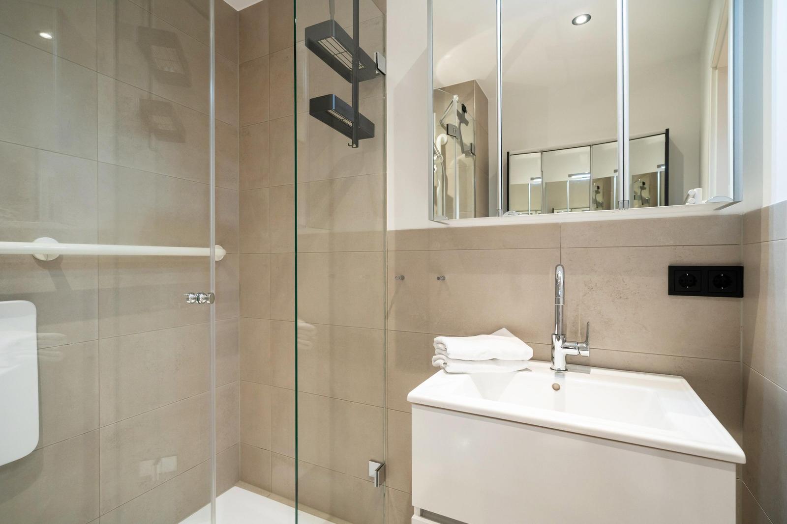 Badezimmer mit Dusche, Waschbecken und Spiegel