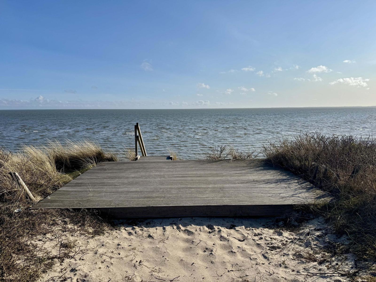Holzterrasse am Strand mit Blick auf das Meer und den Himmel.