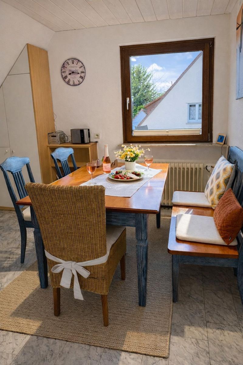 Esstisch mit Stühlen, Fenster und Wanduhr im Raum.