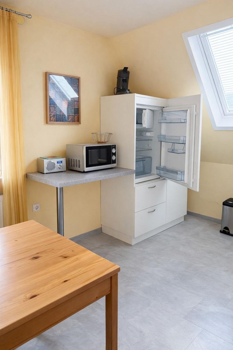 Küche mit Kühlschrank, Mikrowelle und Esstisch.