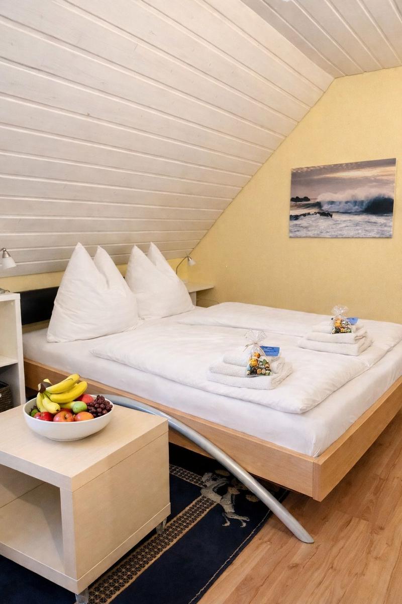Schlafzimmer mit Doppelbett, Früchte auf Tisch und Wandbild mit Wellen.