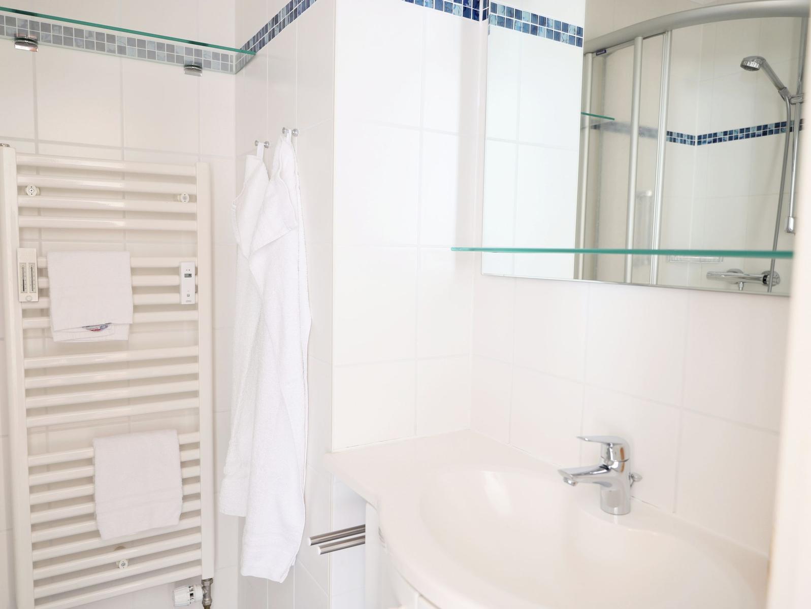 Badezimmer mit Dusche, Waschbecken und Handtuchheizung.