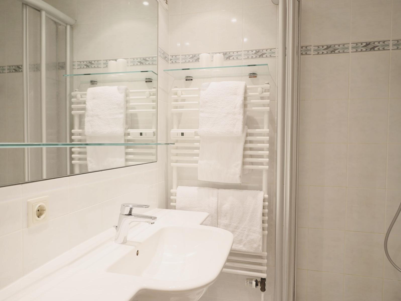 Badezimmer mit Waschbecken, Spiegel und Handtuchhalter