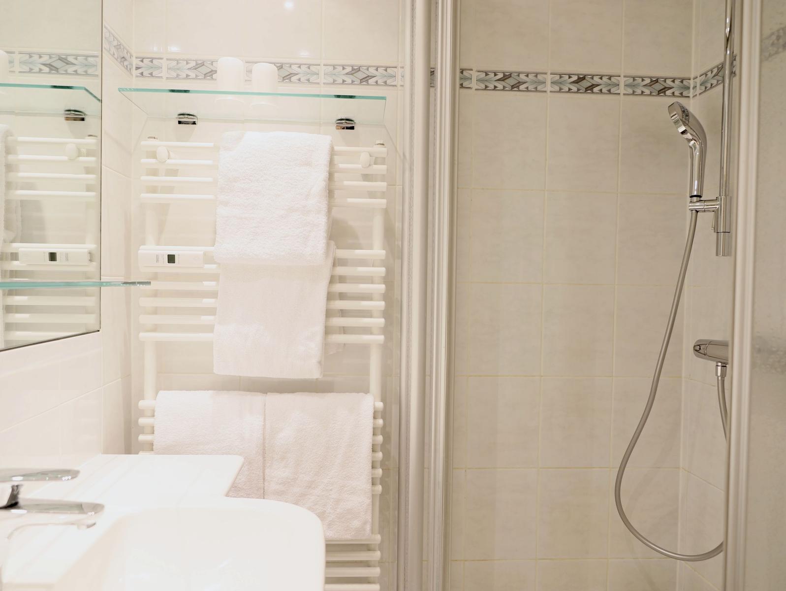 Badezimmer mit Dusche, Handtuchheizung und Waschbecken.