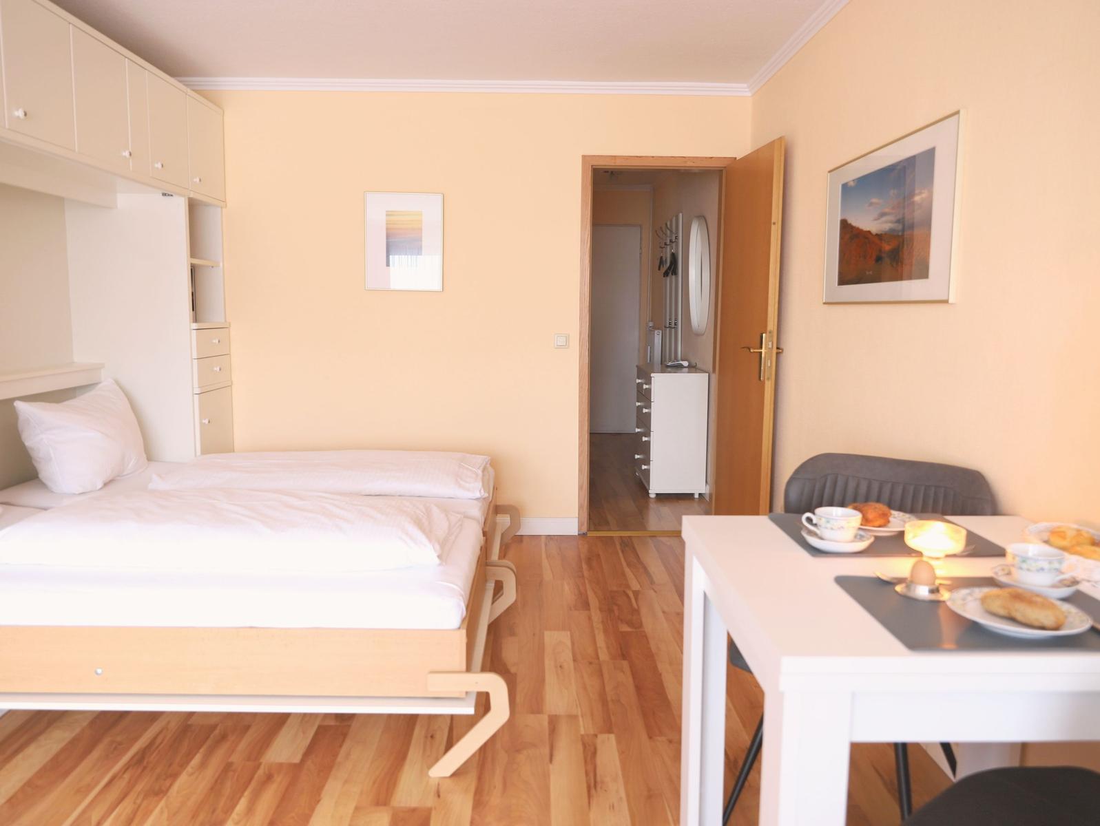 Schlafzimmer mit Bett, Schränken und Tisch mit Frühstück.