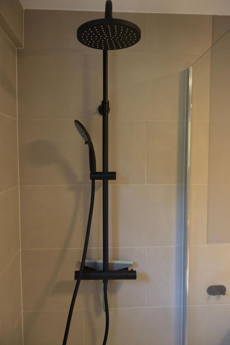 Dusche mit schwarzer Duschkopfhalterung und Handbrause