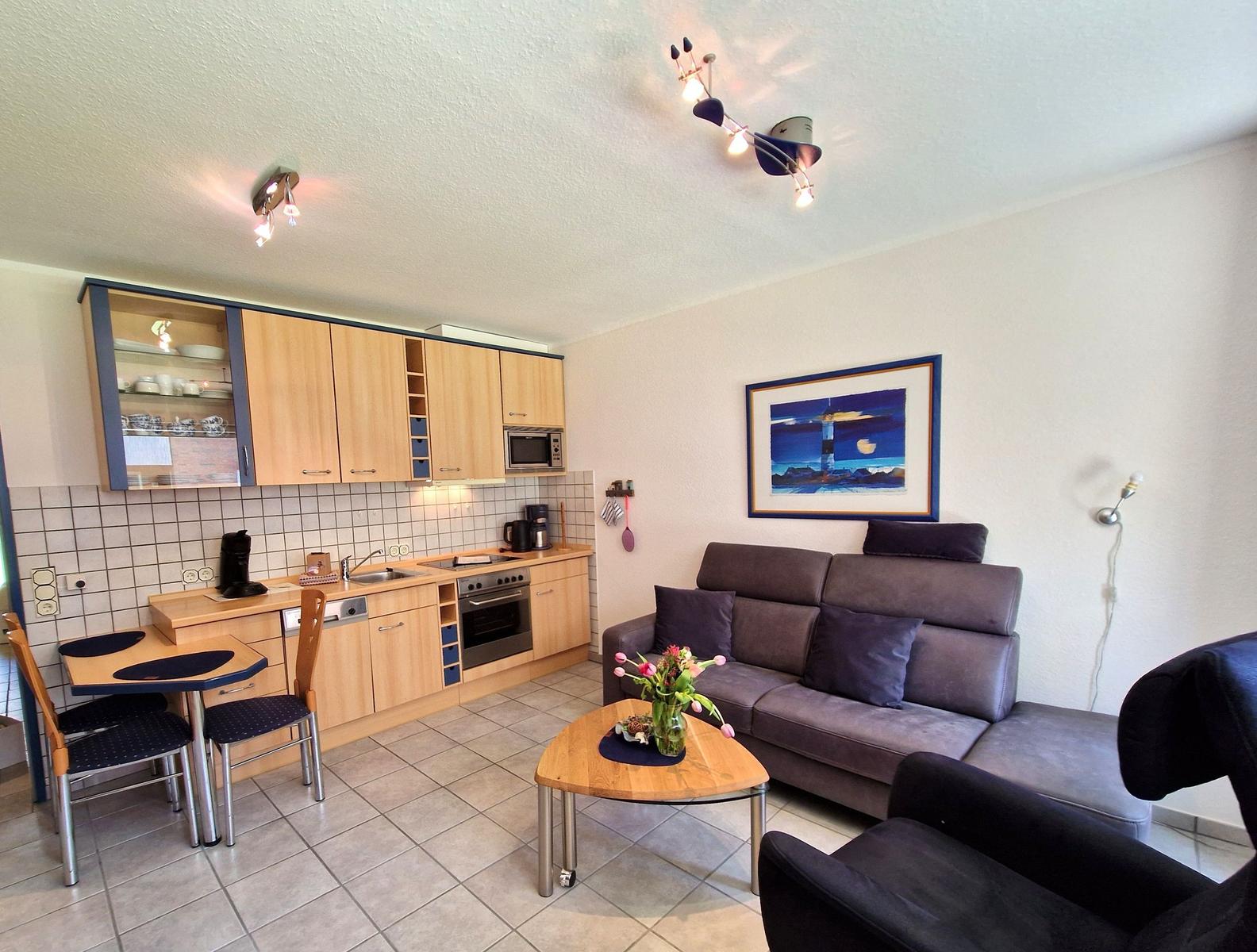 Wohnküche mit Sofa, Esstisch und Kücheneinrichtung.