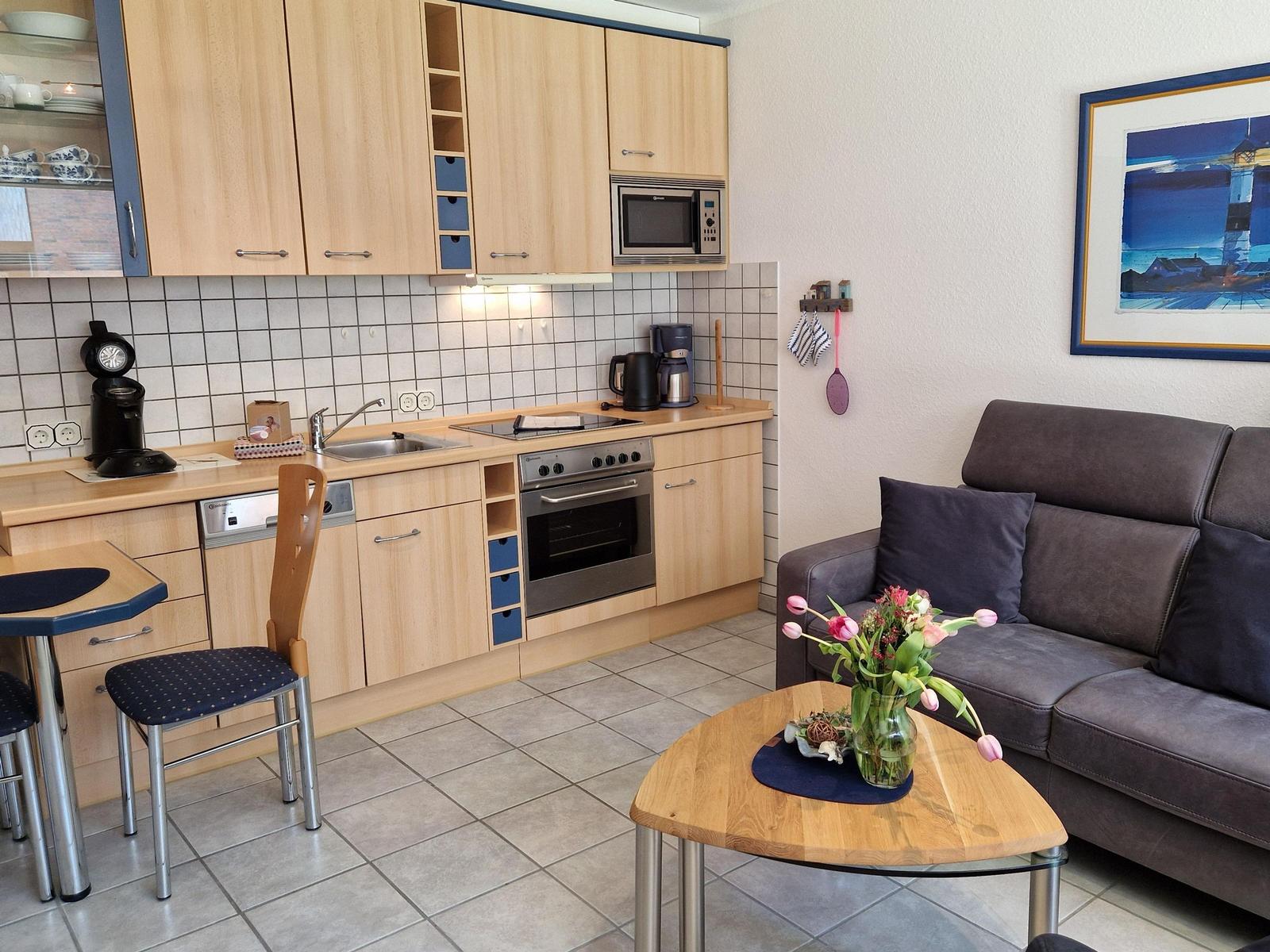 Küche mit Holzschränken und Wohnbereich mit Sofa und Tisch.