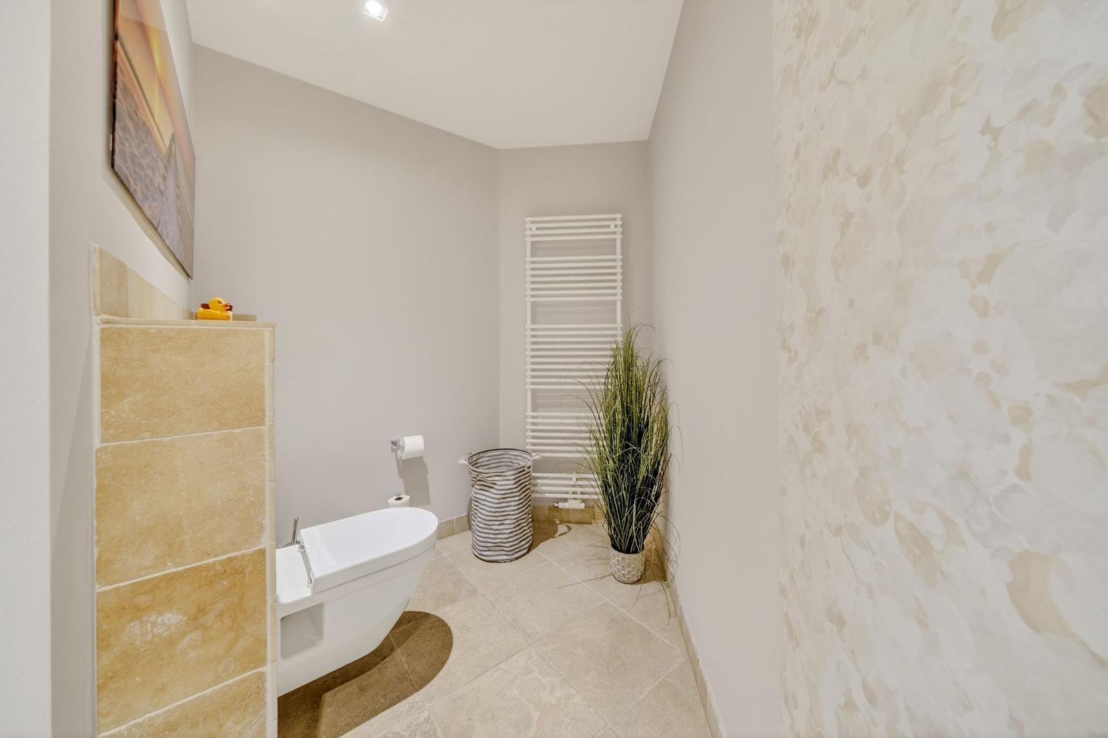 Bad mit Toilette, Heizung, Pflanze und Wandbild.