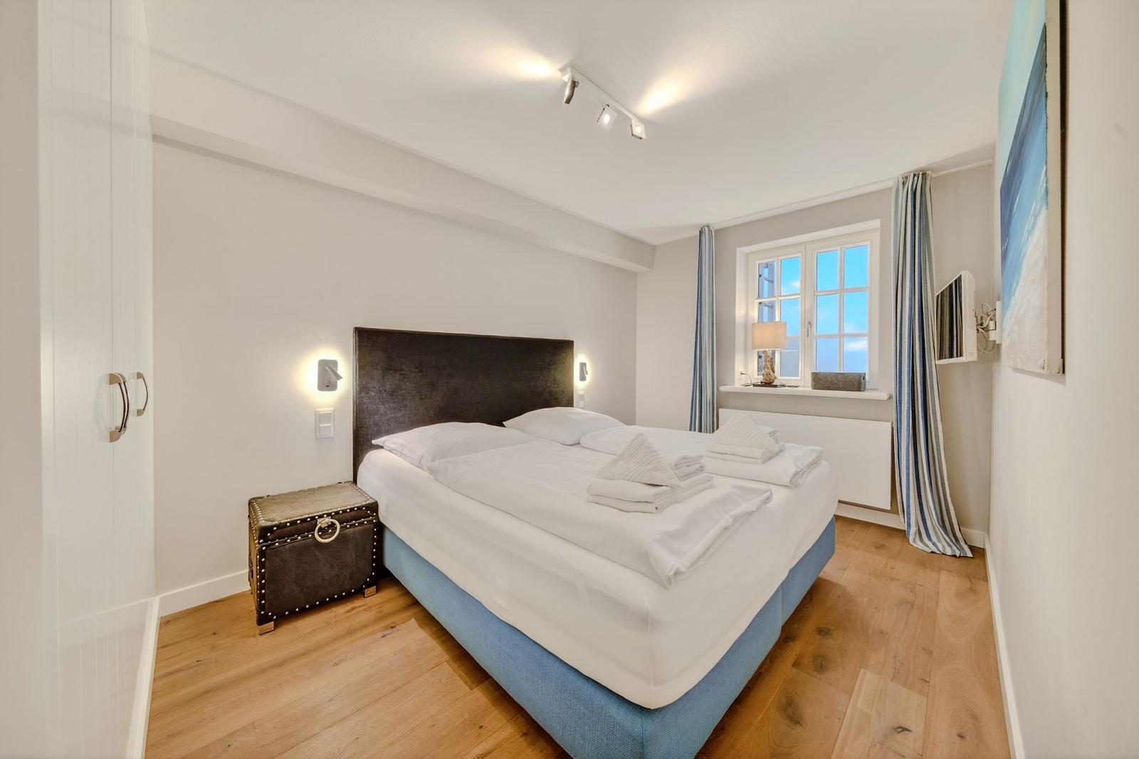 Schlafzimmer mit Doppelbett, Holzboden und Fenster mit Blick.