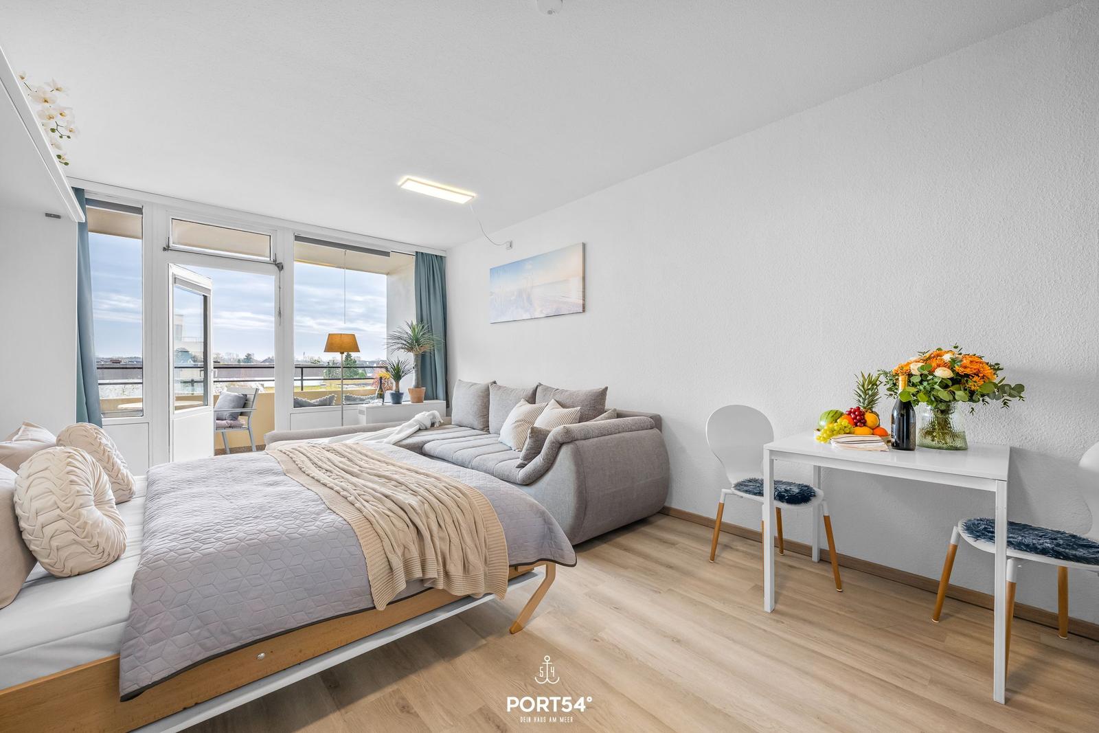 Schlafzimmer mit Sofa, Esstisch und Balkonansicht.