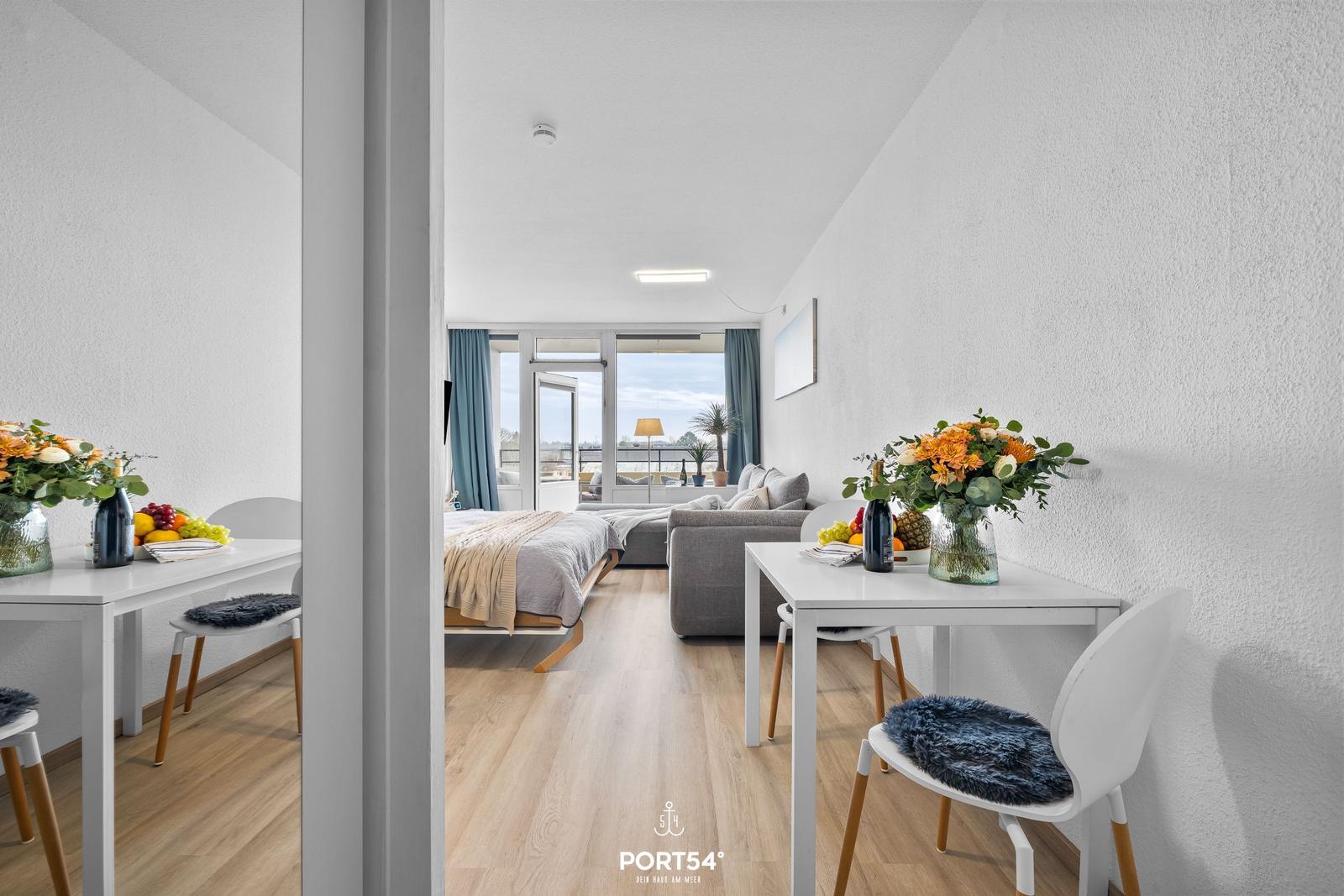 Wohnung mit Schlafbereich, Esstisch und Balkon. Moderne Einrichtung mit Holzboden.
