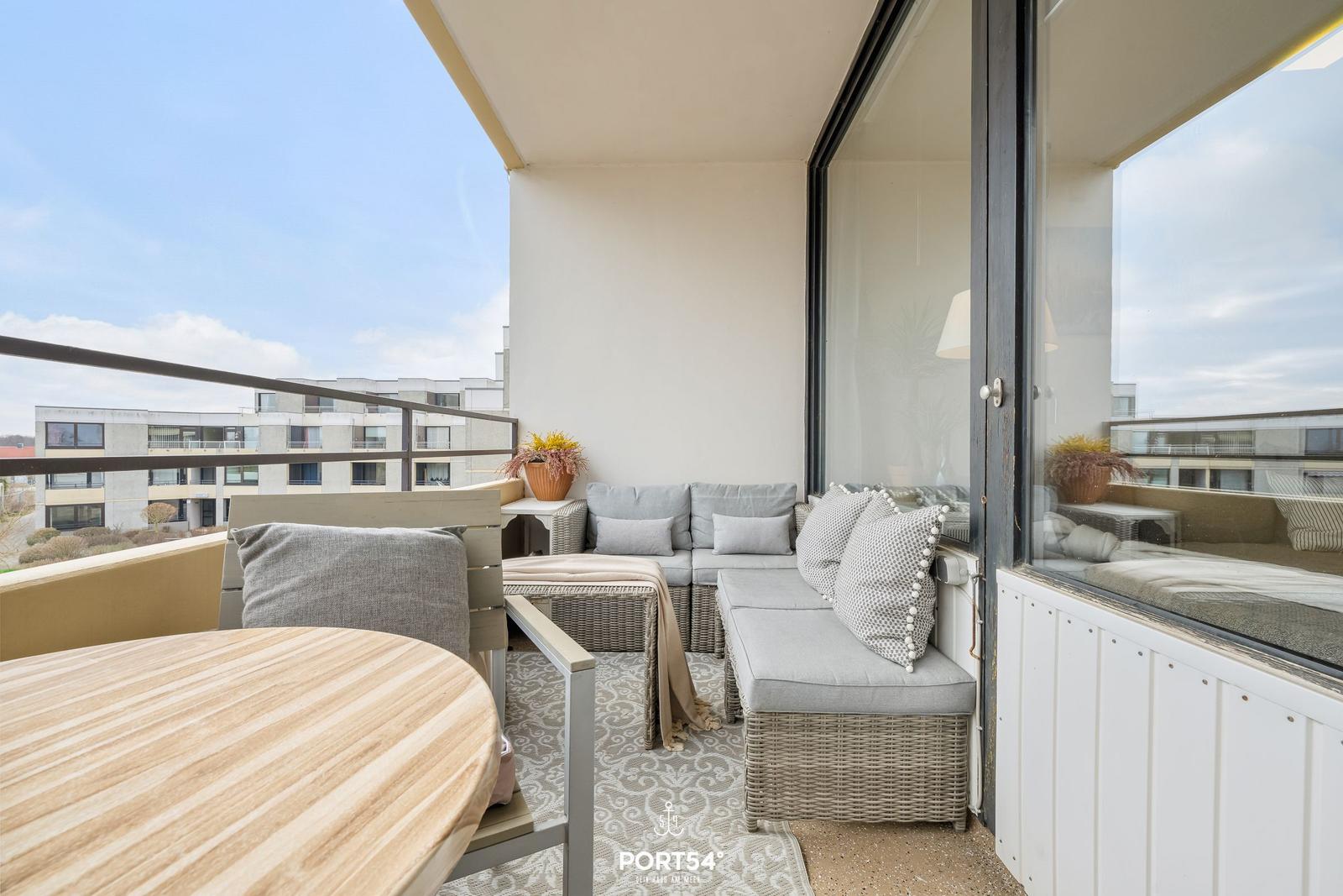 Terrasse mit Sitzgruppe, Tisch und Blick auf Wohngebäude.