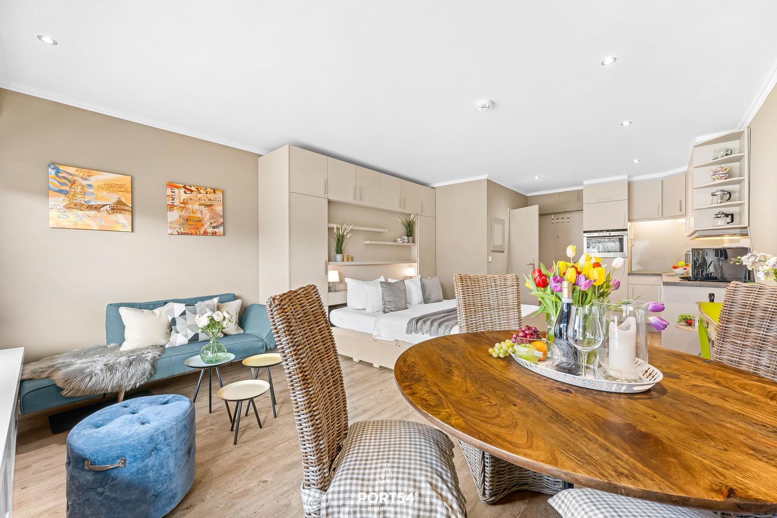 A room with sleeping area, living space, and dining table with chairs.