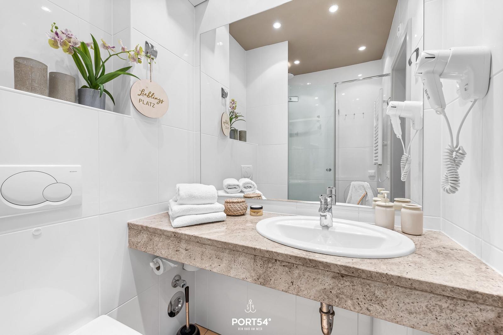 Bathroom with sink, mirror, shower, and towel rack.