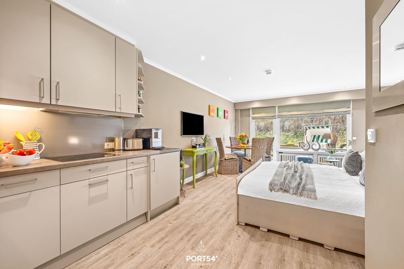 Kitchen with worktop, bedroom with bed and window view.