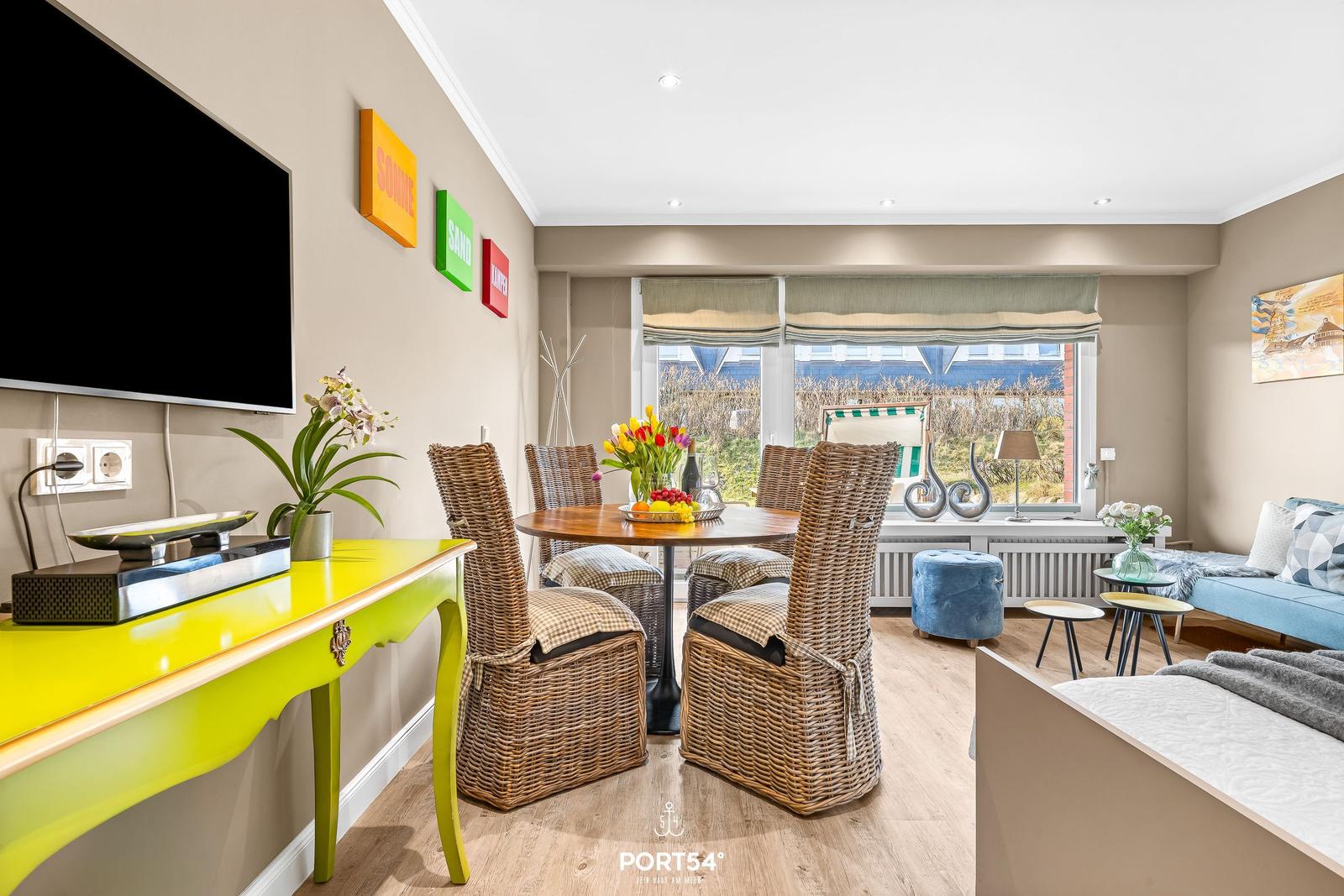Dining room with table, chairs, and TV. Window with view of garden.