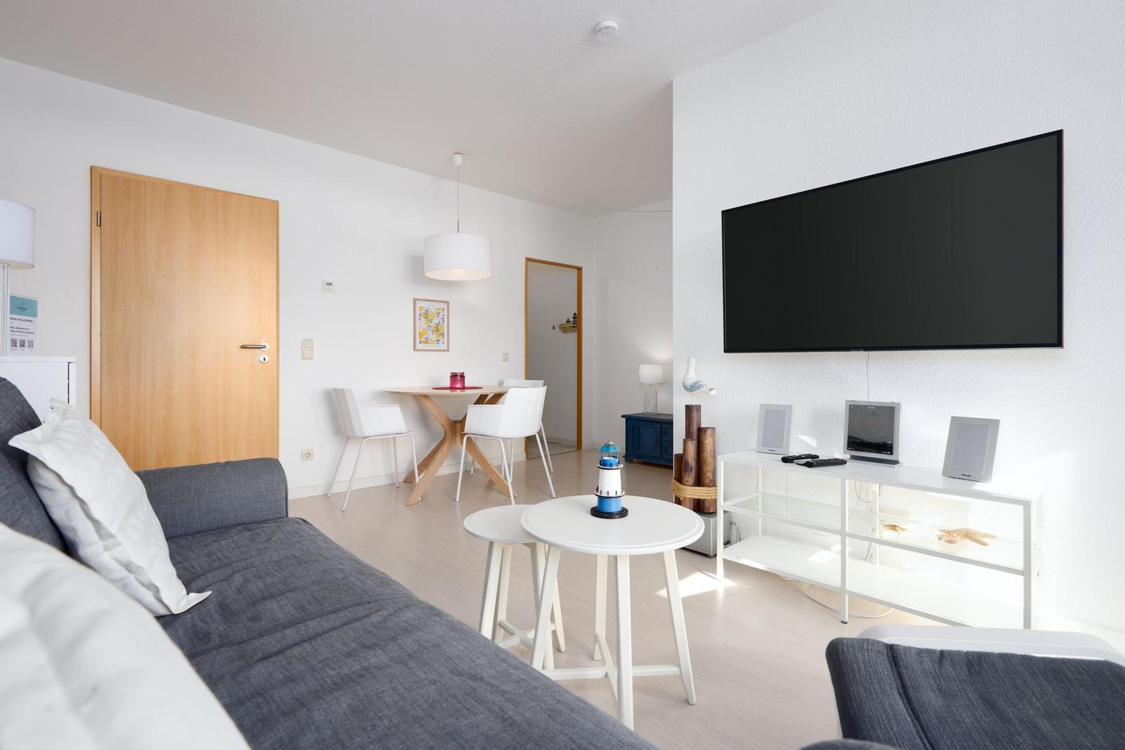 Wohnzimmer mit Sofa, TV und Esstisch. Wandmontierte Anlage.