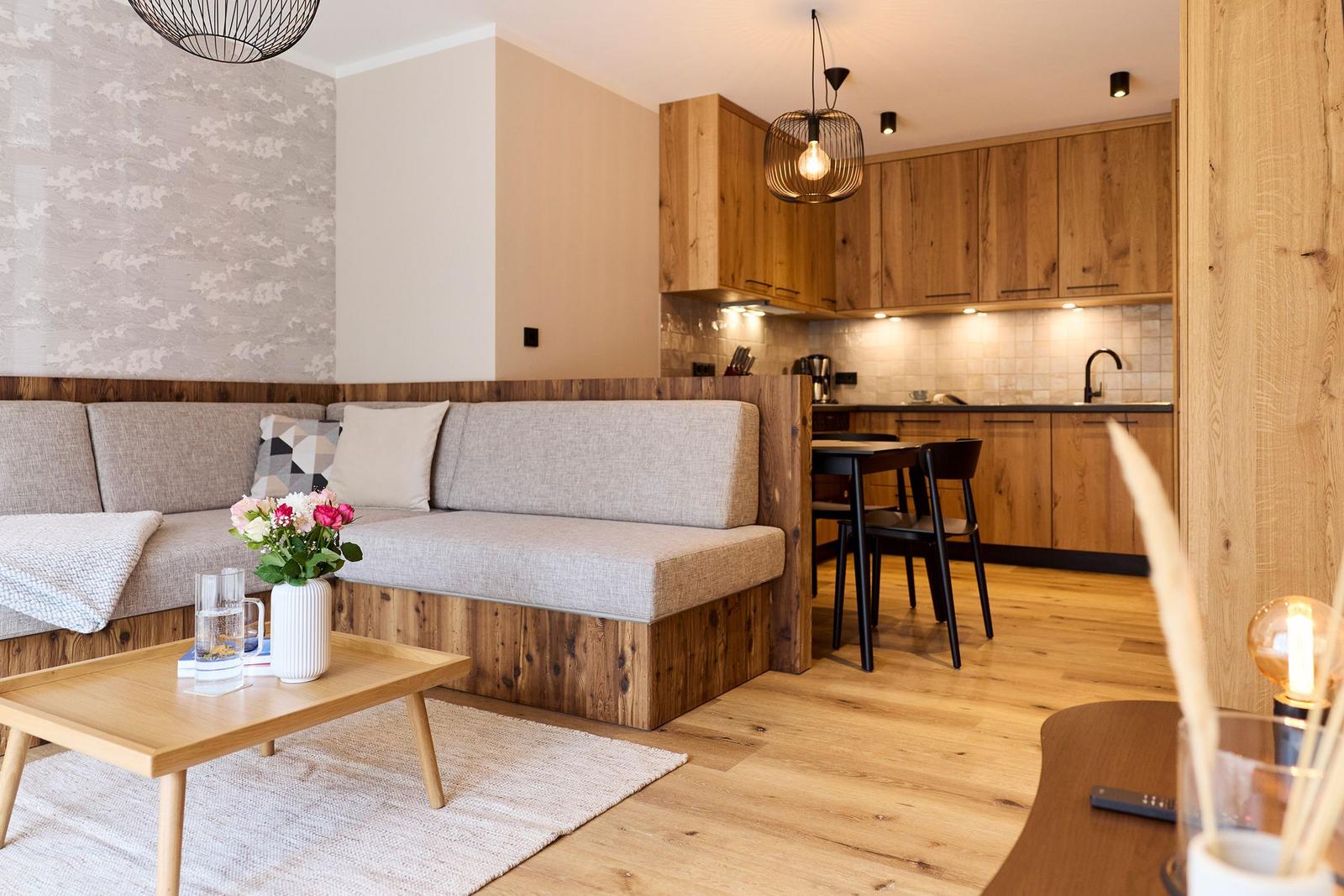 Wohnbereich mit Sofa, Couchtisch und Küche im Hintergrund.