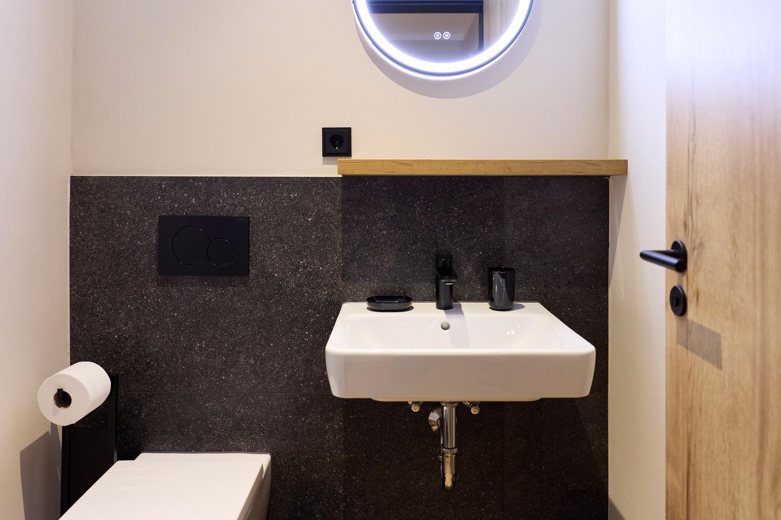 Badezimmer mit Waschbecken, Spiegel und Toilette