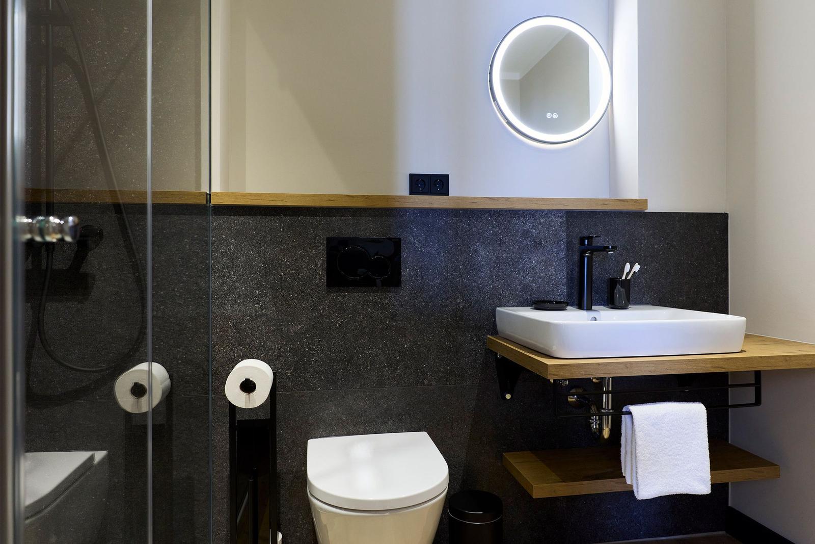 Badezimmer mit Dusche, Toilette und Waschbecken auf Holzuntergestell