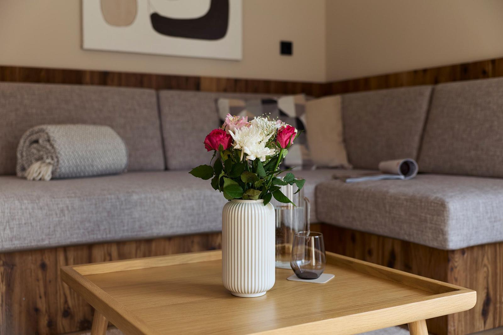 Ein Wohnzimmer mit einem Sofa, einem Tisch und Blumen im Vordergrund.