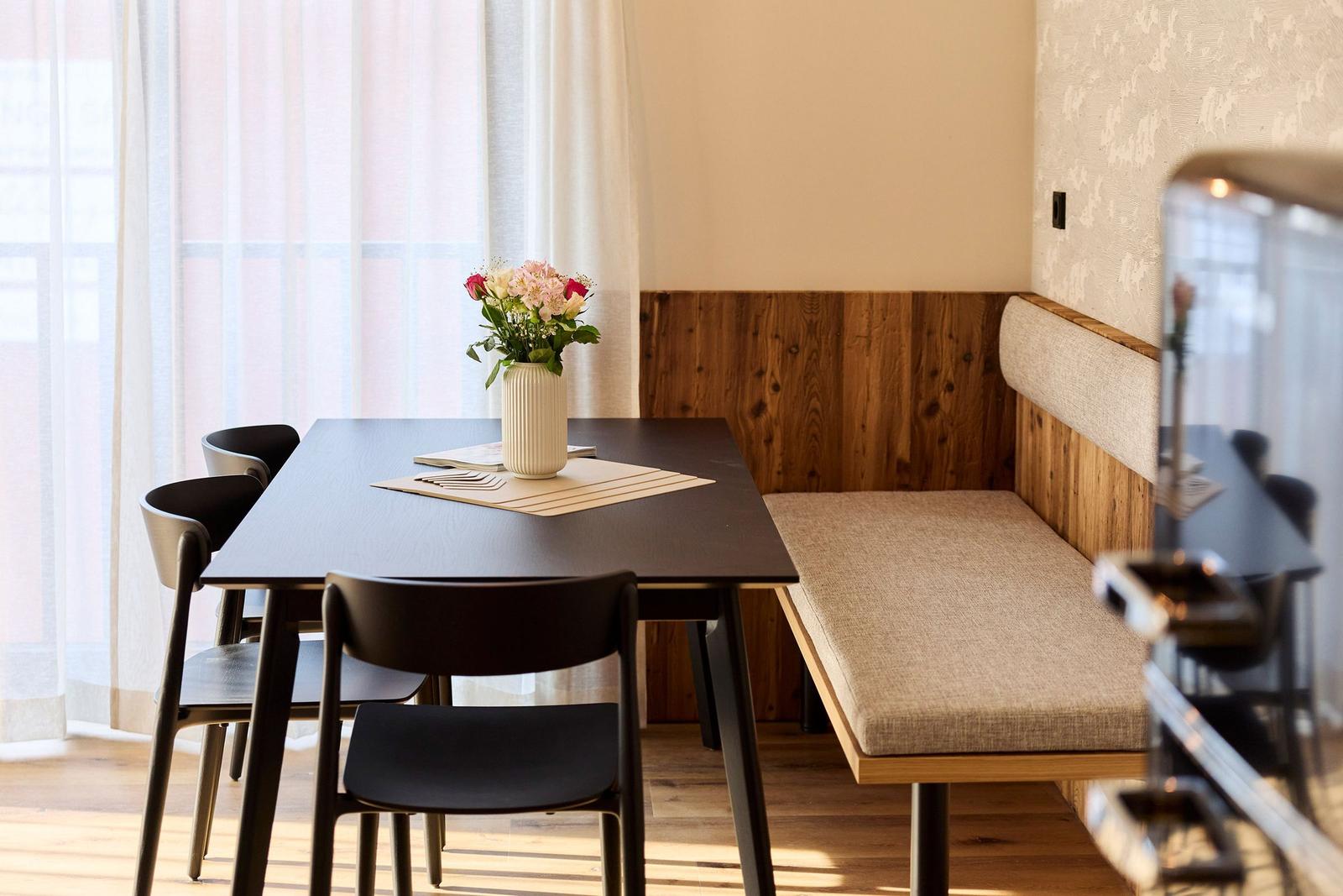 Essbereich mit Tisch, Stühlen und Sitzbank an Holzwand