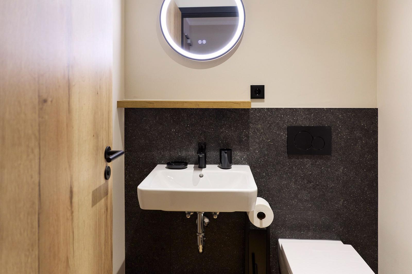 Badezimmer mit Waschbecken, Spiegel und Toilette