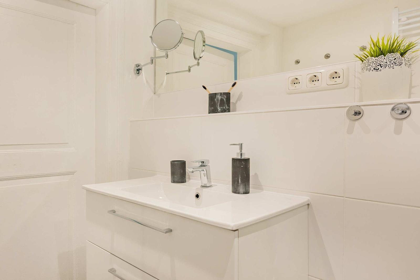 Badezimmer mit Waschbecken, Spiegel und Pflanze.