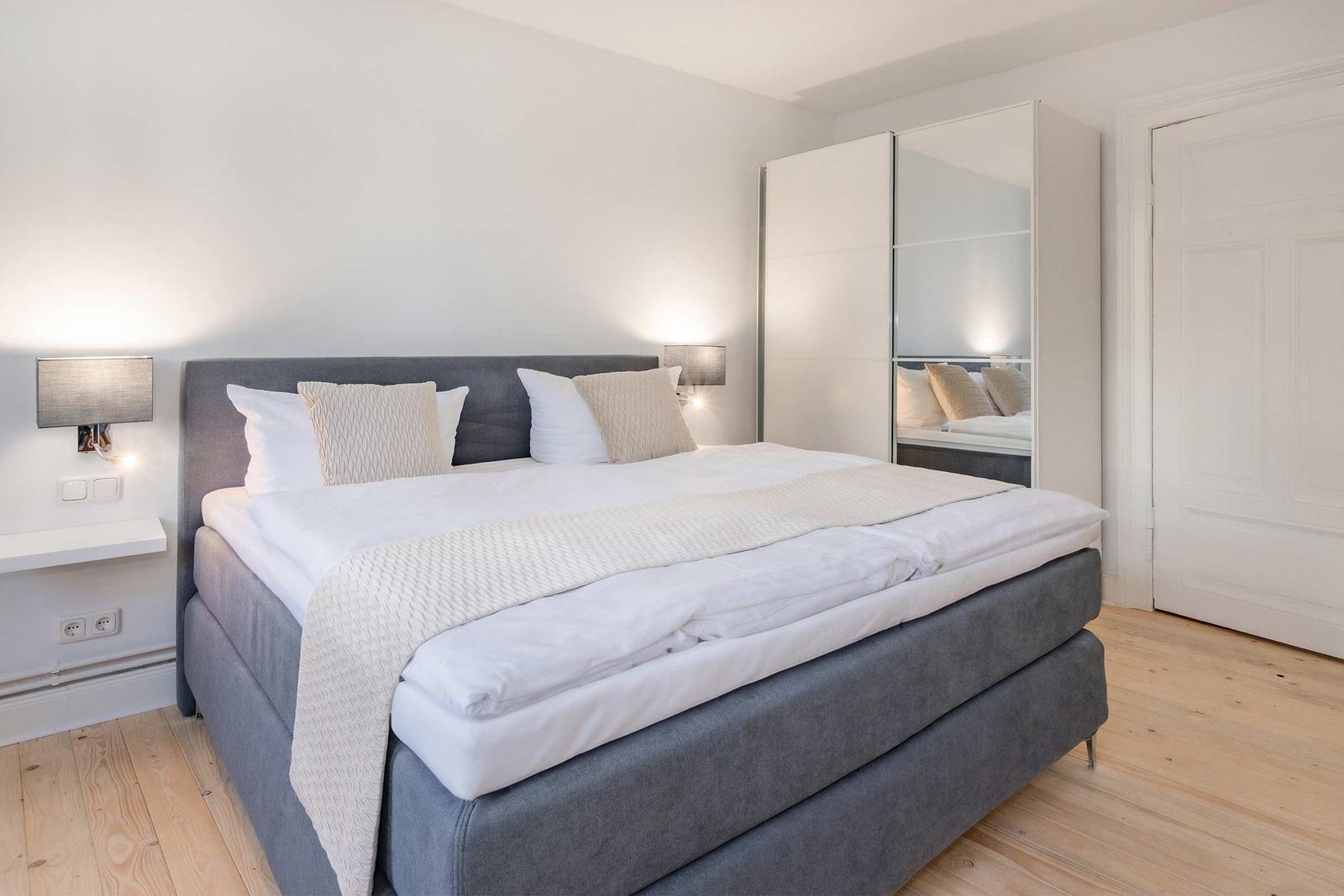 Schlafzimmer mit Bett, Kleiderschrank und Holzboden.