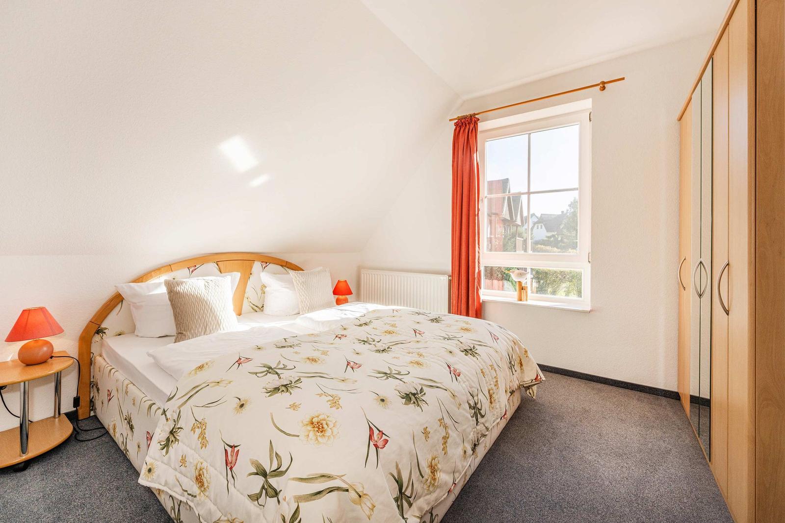 Schlafzimmer mit Bett, Fenster und Kleiderschrank.