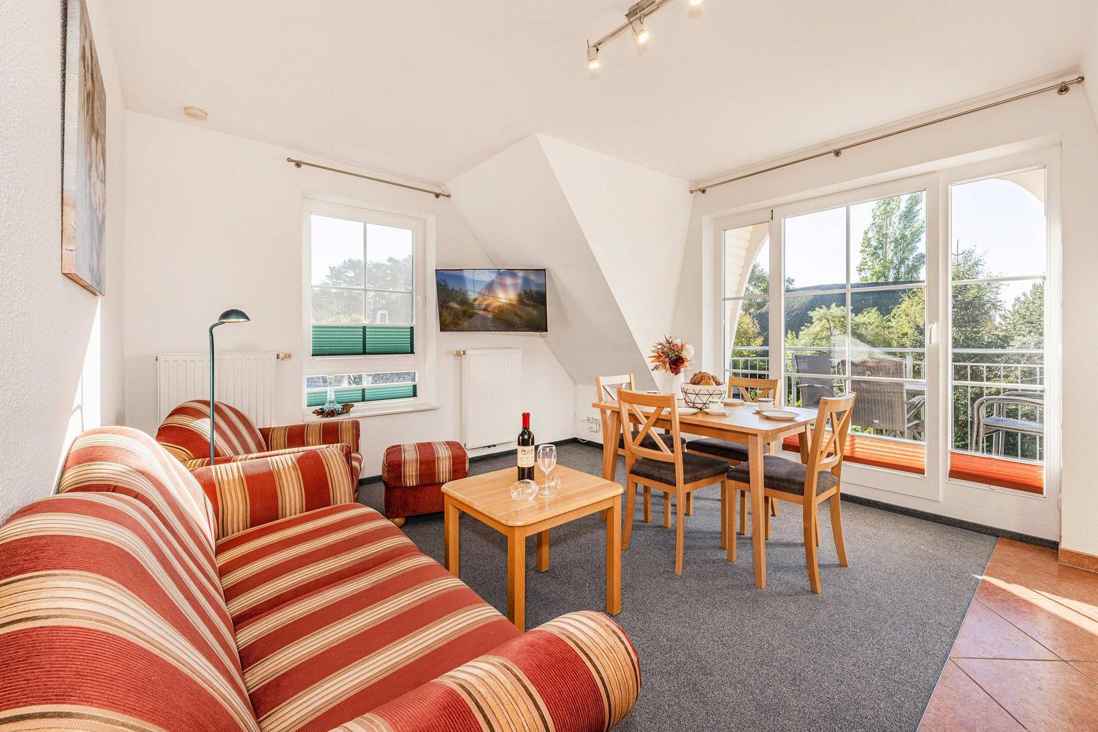 Wohn- und Essbereich mit Sofa, Tisch und Blick auf Balkon.