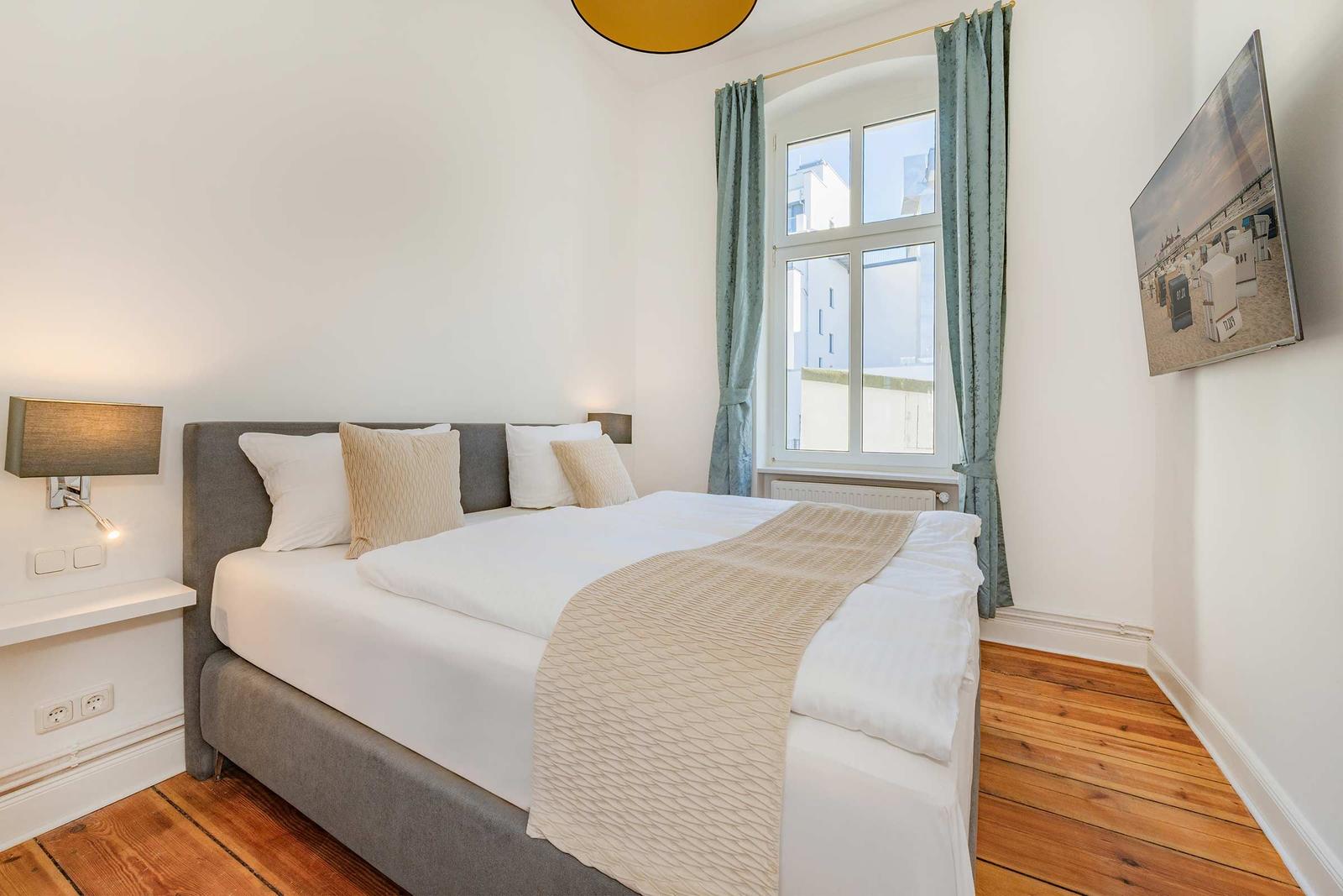 Schlafzimmer mit Bett, Fenster und Holzboden.