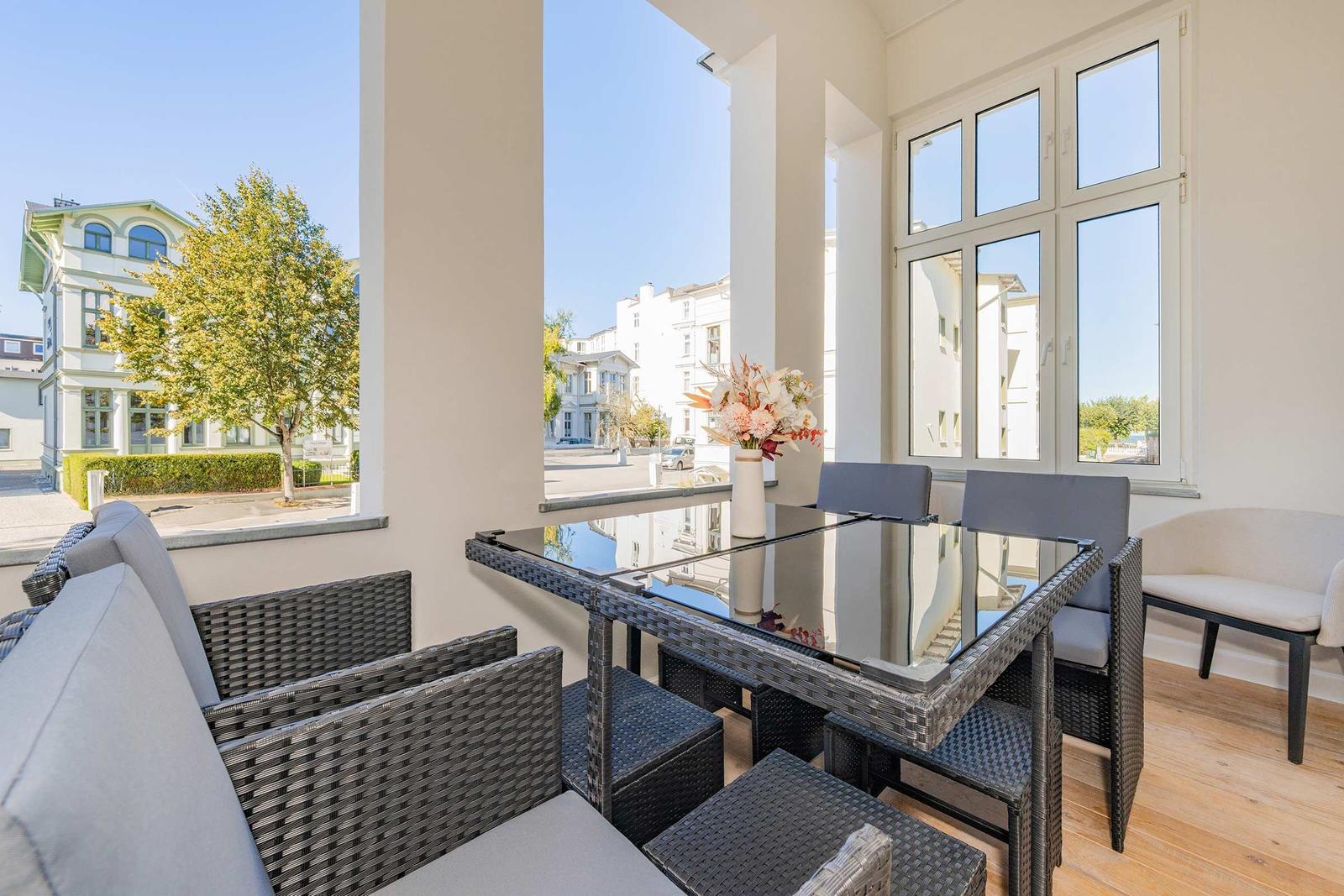 Terrasse mit Sitzgruppe und Tisch. Blick auf Straße und Gebäude.