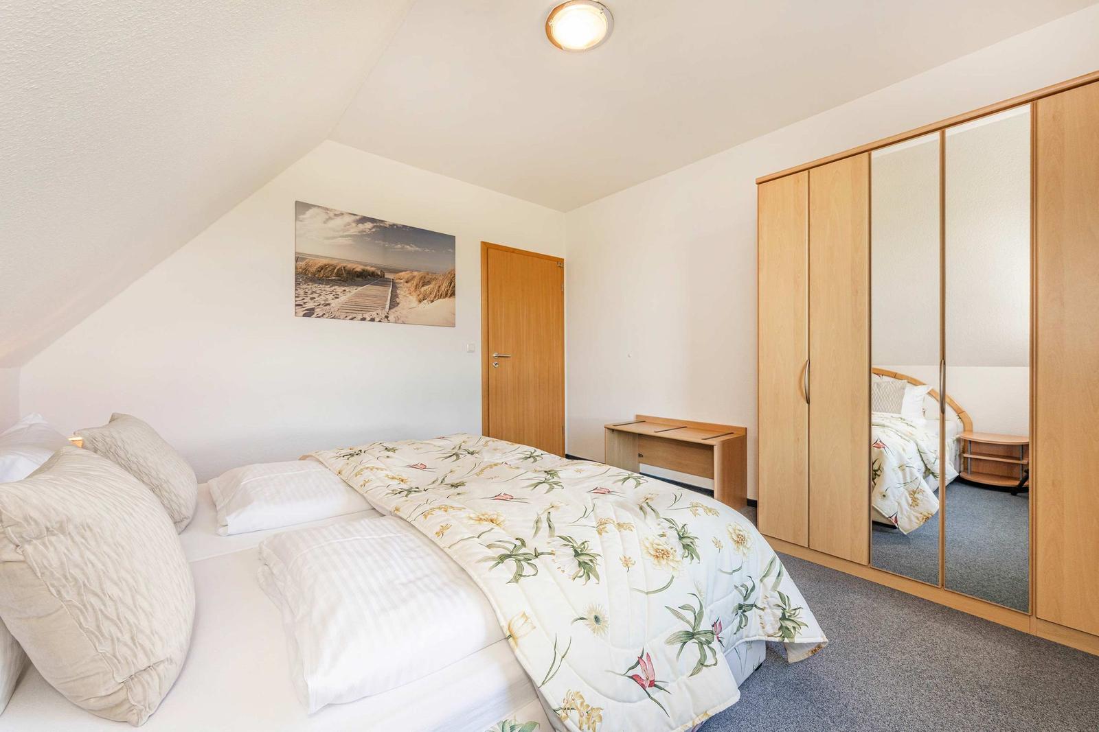 Schlafzimmer mit Doppelbett, Kleiderschrank und Wandbild