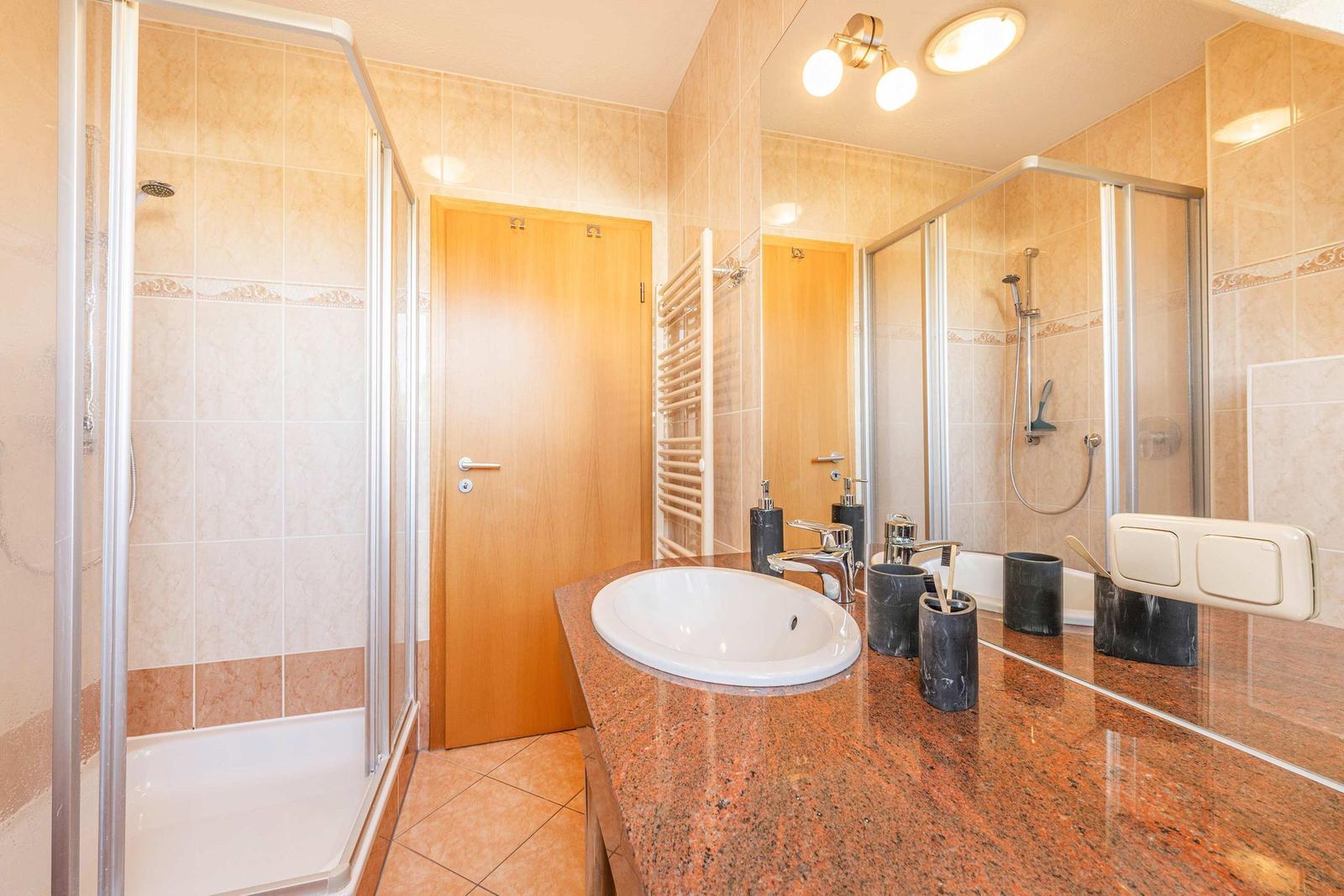 Badezimmer mit Dusche, Waschbecken und Spiegel