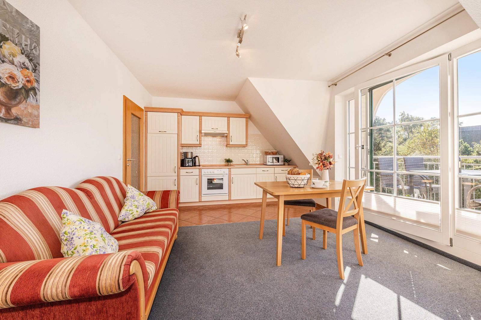 Wohnküche mit Sofa, Esstisch und Balkonansicht