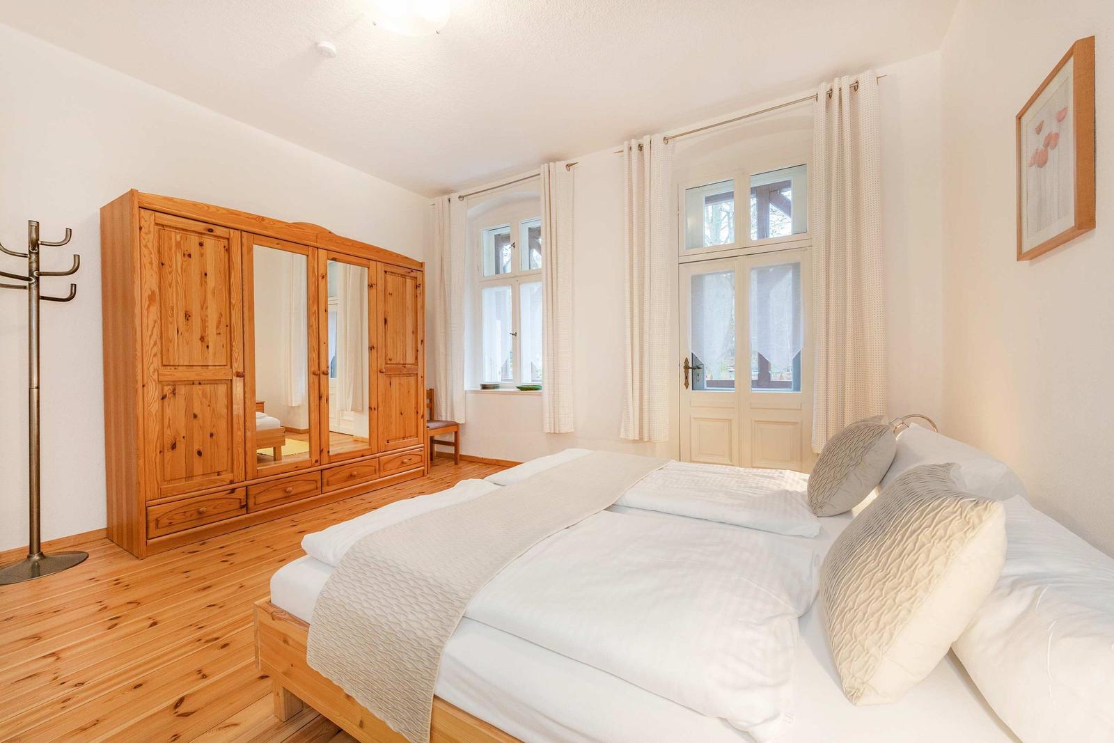 Ein Schlafzimmer mit Holzbett, Kleiderständer und großer Kleiderschrank.