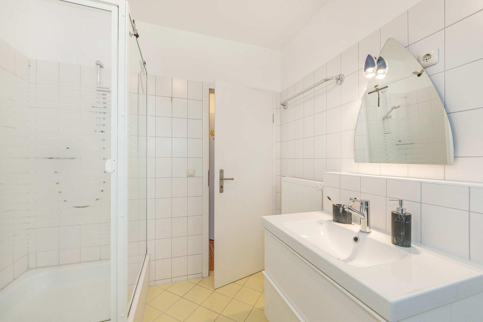 Badezimmer mit Dusche, Waschbecken und Spiegel