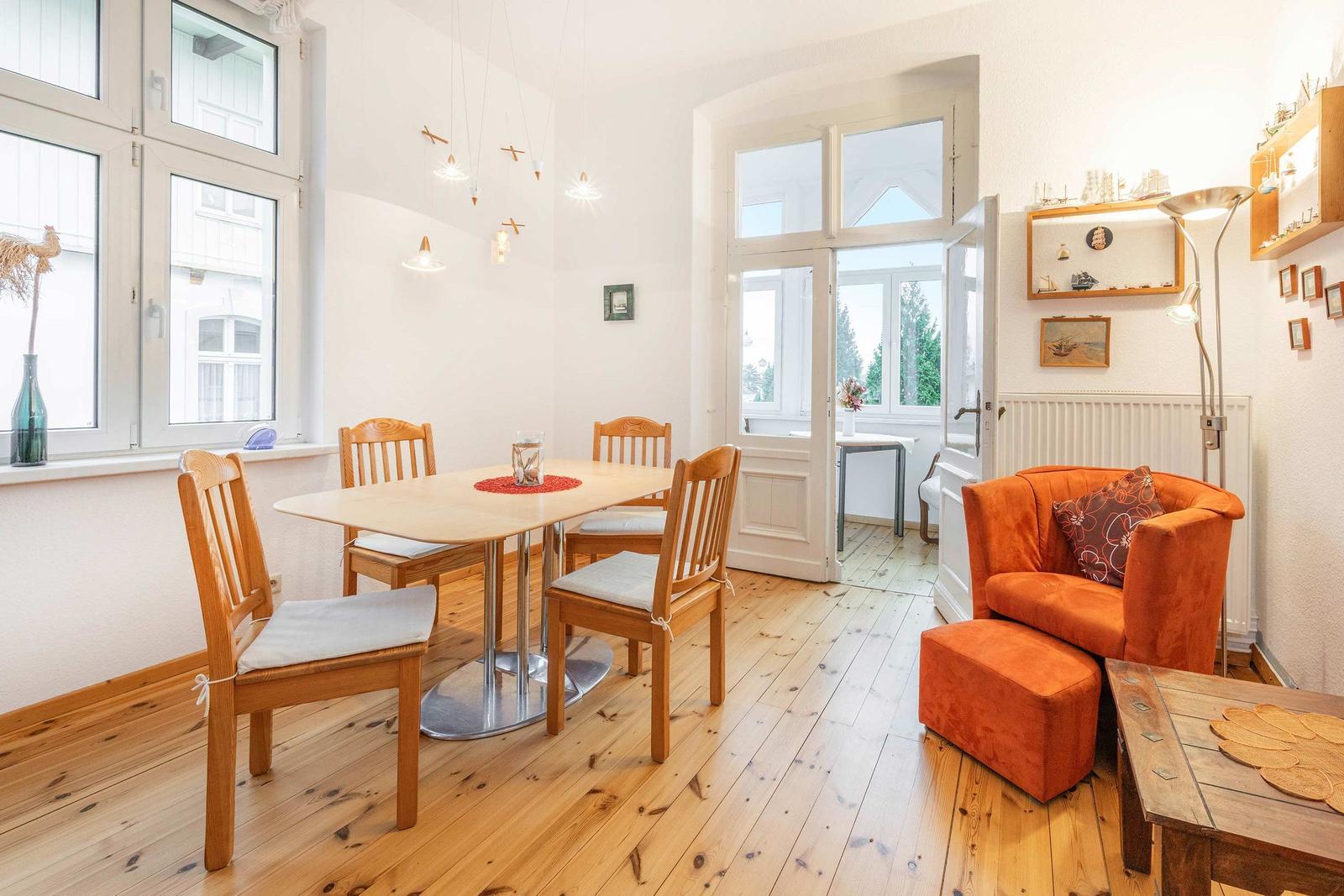 Esszimmer mit Holztisch, vier Stühlen und orangefarbenem Sessel.