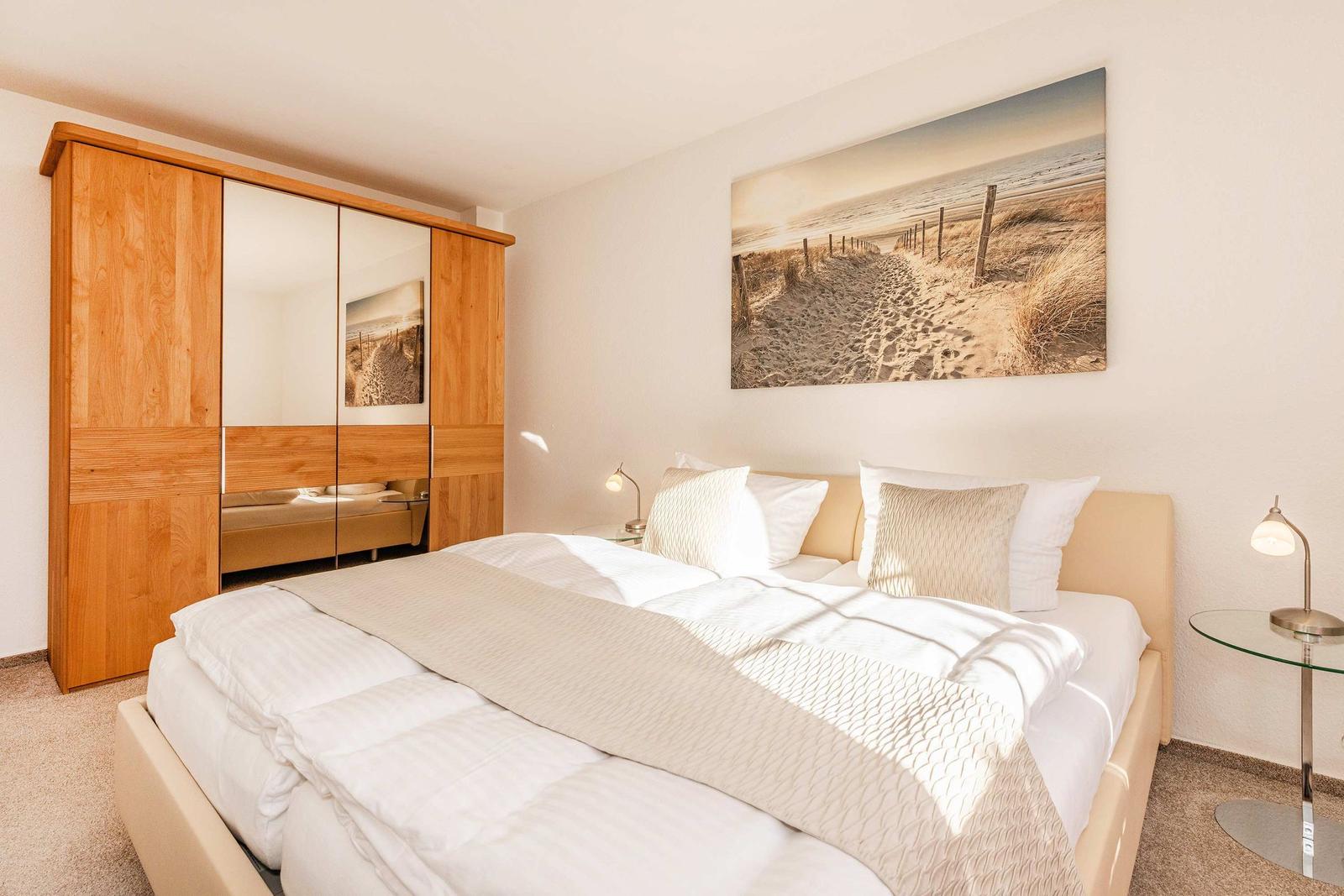 Schlafzimmer mit Bett, Kleiderschrank und Wandbild.