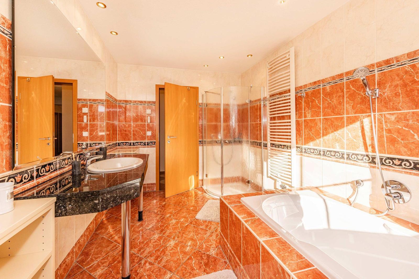 Bad mit Dusche, Badewanne und Waschtisch mit Spiegel.